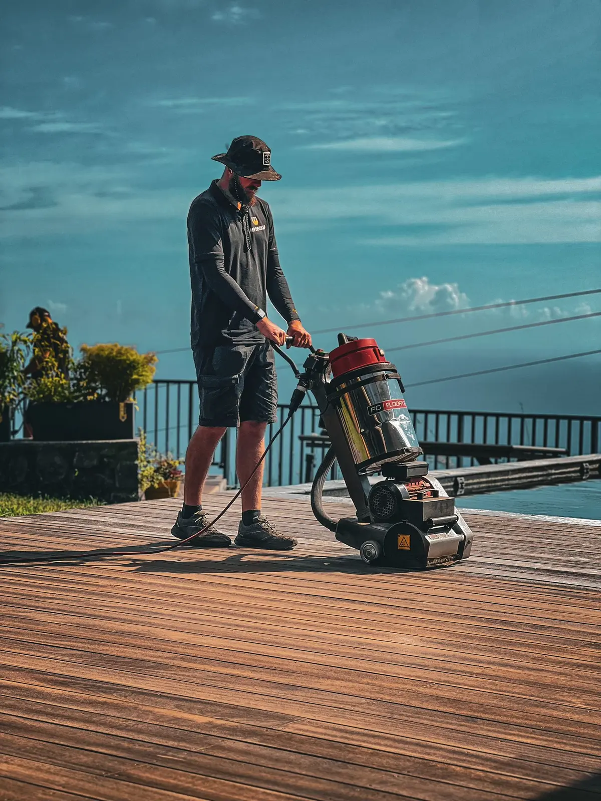 Technicien MR DECKAP utilisant une brosseuse mécanique sur une terrasse en bois à La Réunion